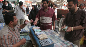 Mandatory Credit: Photo by SABAH ARAR/REX (520708f) An Iraqi money changer exchanges Iraqi dinars for dollars at his open air stall decorated with pictures of Shiite religious figures in the famous al Shorga market. BAGHDAD, IRAQ - 24 APR 2005  (Newscom TagID: rexphotos831111.jpg) [Photo via Newscom]